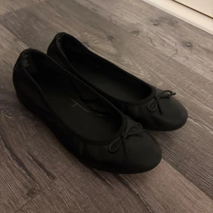 Svarta ballerinaskor  - Snygga svarta ballerinaskor med rund tå och liten rosett framtill. Skorna har en klassisk och stilren design som passar till många olika outfits. Nypris 699 kr