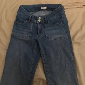 Blåa bootcut jeans från Nelly - Säljer ett par skitsnygga jeans från Nelly med lite bootcut och assnygga fickor/knappar! Står tyvärr ingen storlek men jag skulle säga att de är ungefär 34-36 (eller S). Säljer då dem tyvärr är för små för mig😞 Jag har bara använt dem ett par gånger så de är i mycket gott skick! 