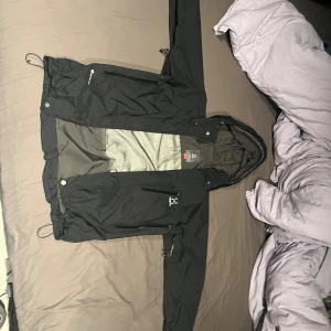 Svart vindjacka från Haglöfs med huva - Storlek L woman sitter som M på män 4000 kr ny pris Svart vindjacka från Haglöfs med justerbar huva, flera dragkedjeförsedda fickor och meshfoder på insidan, snörning i nederkant och är perfekt för utomhusaktiviteter. Snygg och funktionell design med logga på bröstet.