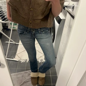 Lee Maddox ljusblå bootcut jeans - Säljer ett par Lee Maddox jeans i ljusblå tvätt med klassiska fem fickor och snygga kontrastsömmar. Modellen har bootcut-ben och låg midja, vilket ger en chill och tidlös vibe. Jeansen är tillverkade i bomull och har Lee-logga på bakfickan.