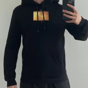 Hoodie - Svart hoodie med tryck fram och bak. Storlek XS.