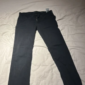 Svarta slim jeansbyxor - Svarta jeansbyxor med smal passform och klassisk femficksdesign. Byxorna har dragkedjegylf och bälteshällor, perfekta för en clean och stilren look. Passar dig som gillar en enkel men snygg stil.