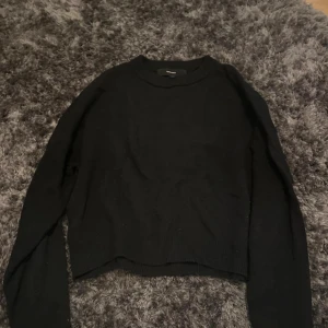 Svart stickad tröja Vero Moda - En svart stickad tröja från Vero Moda i storlek S. Tröjan har rund hals och långa ärmar, med en enkel och clean look som funkar till allt. Mjuk och skön kvalitet, perfekt för kyliga dagar. Snygg att matcha med jeans eller kjol.