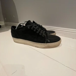 Svarta Lanvin sneakers i skinn och mocka - Lanvin sneakers i svart skinn och mocka med rund tå och platt vit sula. Klassisk låg modell med snörning och stilren design. Perfekt för dig som gillar exklusiva och minimalistiska sneakers med lyxig känsla. Pris kan diskuteras vid snabb affär 🙌🏻
