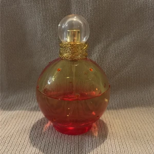 Blissful Fantasy Eau de Toilette - Blissful Fantasy från Britney Spears, 100 ml Eau de Toilette. Snygg flaska med guldiga detaljer, perfekt för dig som vill sticka ut och addera lite glamour till din parfymhylla. Strax över hälften kvar, ca 60%.