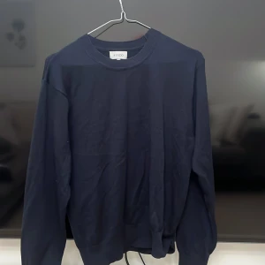 Mörkblå tröja från Sandö, stl S - En stilren mörkblå tröja från Sandö i storlek S. Tröjan har rund halsringning, långa ärmar och är tillverkad i ett mjukt bomullstyg. Perfekt för lager-på-lager och enkel att matcha med jeans eller chinos.