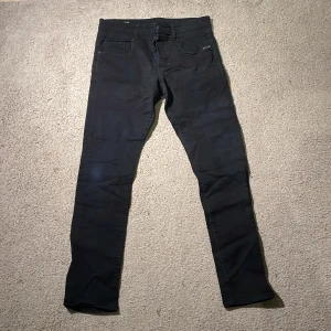 Svarta G-Star RAW Radar jeans tapered - Svarta jeans från G-Star RAW, modellen Radar Tapered. Snyggt smalare passform med klassiska fem fickor och detaljerad bakficka med knapp. Jeansen har en stilren look och är tillverkade i mjukt bomullsmaterial med lite stretch för extra komfort.