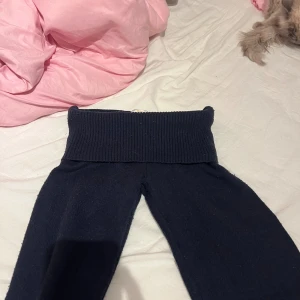 Mörkblå stickade low waist bootcut byxor - Mörkblå stickade byxor med bred ribbad midja och bootcut. Mjukt stickat material som ger en chill och avslappnad vibe. Perfekt för dig som gillar comfy och trendiga plagg med lite extra edge.