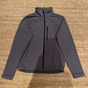 Helly Hansen jacka  - Grå jacka från Helly Hansen.                            Skick: 9,5/10, inga defekter alls.                      Nypris är cirka 1400kr.                                        Skriv vid frågor och kolla in min profil för andra feta plagg🙌