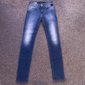 Replay Newluz  jeans blå - Snygga Replay Newluz jeans i klassisk blå tvätt. De har fem fickor, silverfärgad knapp med dragkedja. Jeansen är tillverkade i stretchigt denim för en bekväm och stilren look.