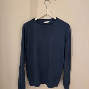 Blå stickad tröja från Kappahl - En stilren blå stickad tröja från Kappahl i storlek S. Tröjan har rund halsringning och långa ärmar, perfekt för lager-på-lager. Enkel och clean design som funkar till allt, med mjukt material som känns skönt mot huden.