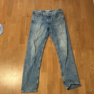 Jack & Jones Loose Fit Jeans Blå 30/34 - Säljer ett par ljusblå loose fit jeans från Jack & Jones, modell Chris. Jeansen har klassisk femficksdesign, raka ben och är tillverkade i bomull. Perfekta för dig som gillar en avslappnad och trendig look.