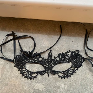 Svart spetsdiadem maskerad - Säljer ett svart diadem i form av en maskeradmask med vackra spetsdetaljer och knytband. Perfekt accessoar för maskerad eller fest, ger en mystisk och elegant look. Masken är lätt och sitter bekvämt med de långa banden.