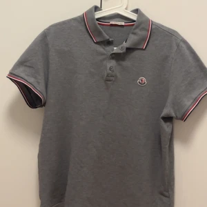 Grå Moncler piké - Priset går att diskuteras .Säljer nu min Moncler pike då den inte används längre, väldigt fint skick den är storlek large men sitter mer som en medium då Moncler är små i storlekarna