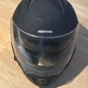 Svart integralhjälm från 4Bikers XS - Säljer en svart integralhjälm från 4Bikers i storlek XS. Hjälmen har visir framtill, ventiler på ovansidan och mjuk grå inredning för extra komfort. Perfekt för dig som vill ha en stilren och säker hjälm till motorcykel eller moped.