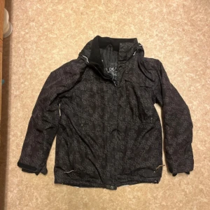 Svart skidjacka  - Svart skidjacka. Trasig söm på höger arm, se bild. 