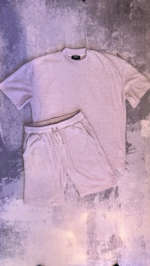 Beige set shorts och t shirt med snyggt mönster från Bohooman - Säljer ett snyggt beige sett med shorts och t shirt från bohooMAN med snyggt strukturerat mönster och resår i midjan med snörning. Settet är i relaxed fit.