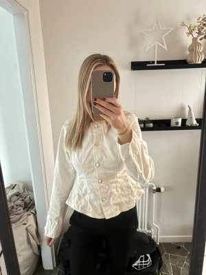 Vit jeansjacka från Gina  - Säljer en fräsch vit jeansjacka från Gina  i storlek 38 men sitter mer som en 36. Jackan har en figurnära passform, rund halsringning och knappar framtill. Materialet är kraftigt denim och jackan har långa ärmar. Perfekt för dig som gillar clean och stilren look. Använd 2 ggr, nypris: 500