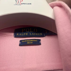 Rosa skjorta från Polo Ralph Lauren - Snygg rosa skjorta från Polo Ralph Lauren i featherweight mesh-material. Klassisk krage, långärmad och med knappar framtill. Perfekt för dig som gillar stilrena plagg med en soft vibe och diskret logga på bröstet. Har bara använt den en gång. Skicket är svinbra den är helt ny