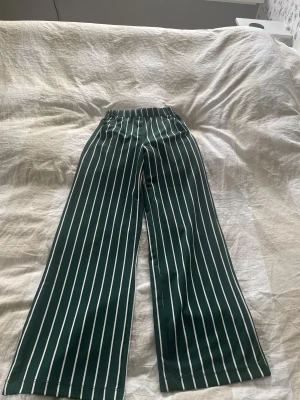 Gröna randiga wide byxor - Snygga gröna byxor med vita ränder och breda ben. De har elastisk midja.