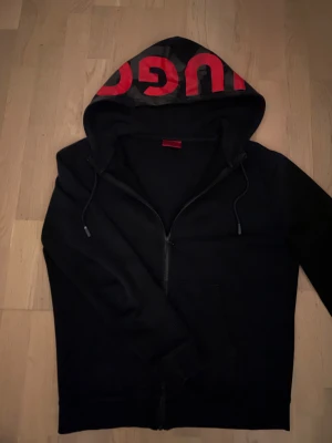 Hugo boss hoodie - Svart hugo boss hoodie med röd fräsh text på huvan. Knappast andvänd, ksk några gånger. Priset är ej huggit är sten, kontakta om intresse🙌