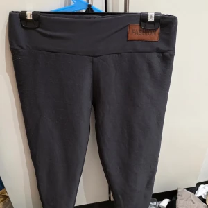 Svarta leggings med fleecefoder XL - Mysiga svarta leggings från Fashion i storlek XL, med mjukt fleecefoder på insidan. Byxorna har hög midja och är tillverkade av stretchigt material med polyester och elastan för extra komfort. Perfekta för kalla dagar när du vill vara både bekväm och snygg.