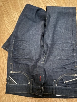 Replay Waitom jeans mörkblå, stl 28 - Säljer ett par Replay Waitom jeans i mörkblå tvätt med klassisk femficksdesign och kontrastsömmar. Regular fit med rak passform och snygga Replay-detaljer på fickorna. Materialet är slitstarkt jeans och midjan är normal.