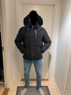 Svart dunjacka från Moose Knuckles - Säljer en Moose Knuckles-jacka i absolut nyskick!  Aldrig använd – endast testad hemma.   Alla originaletiketter, förvaring/dust bag och tillbehör ingår.  Modellen är varm, lyxig och perfekt för svenska vintern, med den ikoniska loggan på ärmen. Sitter fantastiskt och håller riktigt hög premiumkvalitet.  Perfekt som julklapp till någon som vill ha något exklusivt och helt nytt.  Passar perfekt för dig mellan 173 - 180 cm.