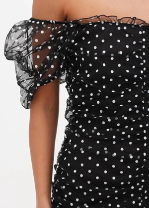 Svart prickig klänning  - Svart kortklänning med vita prickar och puffiga offshoulder-ärmar i mesh. Klänningen har rynkade detaljer längs hela kroppen. Materialet är tunn mesh med undertyg mot kroppen. 