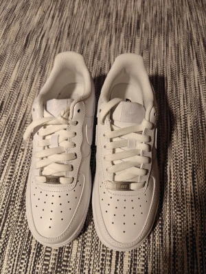 Nike Air Force 1 vita sneakers - Säljer ett par helt nya vita sneakers i storlek 39 då de inte passade. Sjukt bra kvalitet men kan ej verifiera dess äkthet, därav pris.