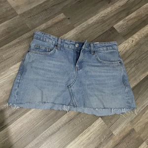 Ljusblå jeanskjol med rå kant - Säljer en ljusblå jeanskjol med klassiska fickor fram och bak, bälteshällor och rå, fransig kant nedtill. Kjolen har en rak passform och stängs med knapp och dragkedja framtill. Perfekt för en avslappnad och trendig look. Den är klippt o sytt av ett par lågmidjade Zara jeans, tyckte inte den passade mig💗