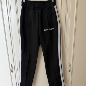 Svarta Palm Angels byxor - Svarta byxor från Palm Angels med vita sidoränder och logga på låret ( Rep )