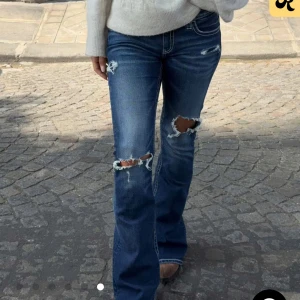 Blå bootcut jeans med slitningar - Snygga blå bootcut jeans från Gina 14+ med slitna detaljer och hål på knäna. Jeansen har kontrastsömmar och broderade bakfickor som ger en cool look. Tillverkade i klassiskt denimtyg med låg midja och utsvängda ben. Helt nya med prislapp endast testade. Storlek S. Normal i storlek. 