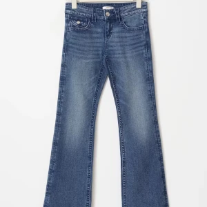 Blå lågmidja bootcut jeans med kontrastsömmar  - Snygga blå jeans med bootcut-modell och tydliga vita kontrastsömmar. Klassisk femficksdesign och dubbla knappar i midjan. Perfekta för dig som gillar en avslappnad men ändå trendig look. Size 158 Young men passar som xs 