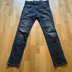 Replay Anbass svarta jeans slim fit - Säljer ett par Replay Anbass jeans i svart tvätt med snyggt slitna detaljer. Jeansen har fem fickor, dragkedjegylf och smal passform som sitter tajt längs benen. Materialet är stretchigt jeans för extra komfort. Perfekta för dig som gillar en modern och stilren look. W30/L30