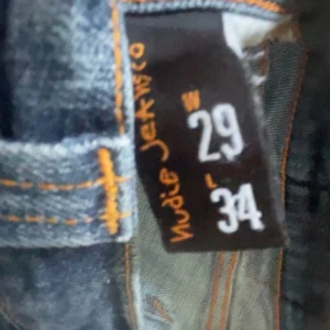 Blå skinny jeans från Nudie Jeans Co - Säljer ett par klassiska blå jeans från Nudie Jeans Co i modellen . Jeansen har orangea sömmar,4 fickor och snygga detaljer på bakfickorna. Perfekt passformo och tillverkade i slitstarkt denimtyg.