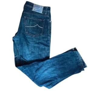 Mörkblå jeans från Jacob Cohen - Snygga mörkblå jeans från Jacob Cohen med klassisk femficksdesign och kontrastsömmar på bakfickan. Jeansen har rak passform och är tillverkade i slitstarkt denim. Perfekta för dig som gillar en tidlös och stilren look. Style 688