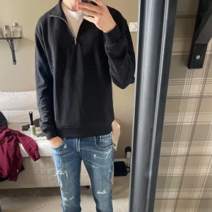Svart half zip-tröja Jack & Jones - Svart långärmad tröja från Jack & Jones med half zip-dragkedja vid halsen. Tröjan har en klassisk passform och är gjord i mjuk bomull, perfekt för en chill och stilren look. Enkel att matcha med jeans eller joggers. Inte kommit till användning så som jag hoppas med inga fel på tröjan! Hör av dig om du har några funderingar 