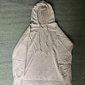 Helt ny Beige hoodie i merinoull - Mjuk och stilren beige hoodie i merinoull med huva och snörning. Tröjan har långa ärmar, ribbade muddar och en relaxed passform. Perfekt för dig som gillar en clean och enkel look med premiumkänsla.