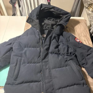 Cana goose jacka macmillan parka - Säljer en mörkblå canada goose jacka som endast använts 1 vinter. Jackan är i bra skick och har inga defekter. Passar S/M. Bara att höra av sig vid frågor 