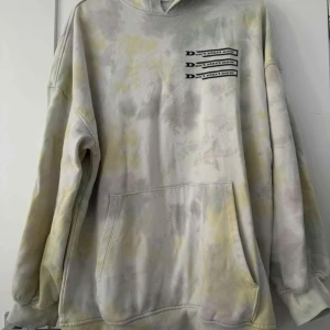 Oversized tie-dye hoodie med tryck - Säljer en oversized hoodie i ljusa tie-dye färger med gult och grått. Tröjan har huva, stor magficka och tryck med texten 'Don't start now' på bröstet. Perfekt för chill dagar och streetstyle.