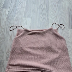 Ljusrosa linnetopp med tunna axelband - Säljer en ljusrosa linnetopp med tunna axelband och rak halsringning. Toppen har en lätt strukturerad yta och är ärmlös, perfekt för varma dagar. Tyvärr finns de inte någon lapp så vet varken märke eller storlek, men skulle säga att linnet är xs/s