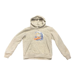 Grå hoodie Polo Ralph Lauren M - Grå hoodie från Polo Ralph Lauren i storlek M med en cool surfande björn på bröstet. Tröjan har huva, magficka och ribbade muddar. Materialet är mjuk bomull och polyesterbladning, passformen är normal.