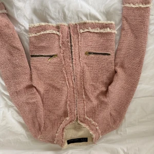 Rosa cardigan jacka från Zara Basic - Rosa cardigan jacka från Zara Basic med råa kanter och två snygga dragkedjefickor framtill. Jackan har lång ärm och är tillverkad i ett mjukt, stickat material med ljusa detaljer längs kanterna. Passar Xs-S