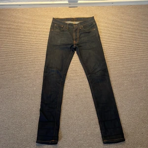 Nudie Jeans Lean Dean - Säljer ett par mörkblå Nudie Jeans i modellen  Lean Dean, skick 7,5/10 dem skulle kunna behöva  en tvätt men annars så är den näst intill nya förutom lite fade på ena bakfickan och framfickan 