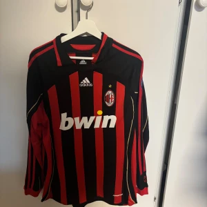 AC Milan långärmad Maldini tröja Adidas - Säljer en klassisk AC Milan långärmad fotbollströja från Adidas med Maldini #3 på ryggen. Tröjan är svart och röd med guldiga detaljer, klubbmärke, Champions League-märke på ärmen och broderad 'Rossoneri' i nacken. Tillverkad i funktionsmaterial.