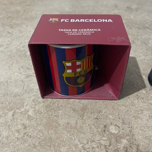 FC Barcelona Ceramic Mug - Snygg FC Barcelona-keramikmugg i originalförpackning, perfekt för fans och samlare. Muggen har klubbens emblem och klassiska färger. Skicket är mycket bra, inga synliga skador eller slitage. Perfekt som present eller till morgonkaffet.
