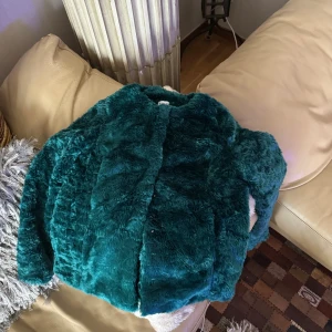 Mörkgrön pälsjacka från Gina Tricot - Säljer en fluffig och mjuk mörkgrön pälsjacka från Gina Tricot. Jackan har lång ärm och en oversized passform som ger en cool vibe. Perfekt för att sticka ut med färg och stil under kyliga dagar.
