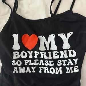 Svart linne med tryck och hjärta - Säljer ett svart linne med smala axelband och ett stort tryck i vitt och rött på framsidan. Aldrig använd. 