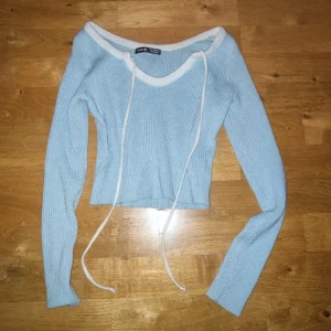 Ljusblå ribbad topp  - Säljer en ljusblå ribbad långärmad topp från Shein med vit kant och snörning vid halsen. Perfekt för dig som gillar stilrena detaljer och mjuka färger.